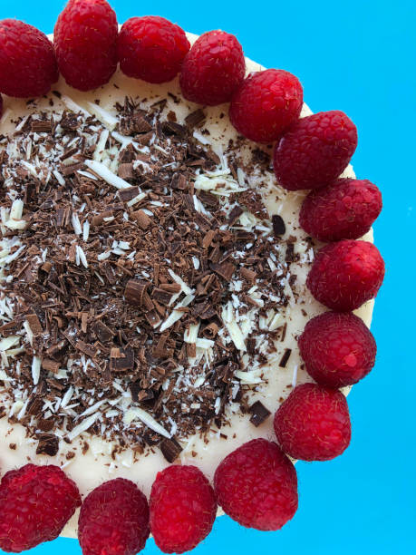 Image of uncut gourmet homemade raspberry cheesecake cake dessert with grated chocolate and red berries