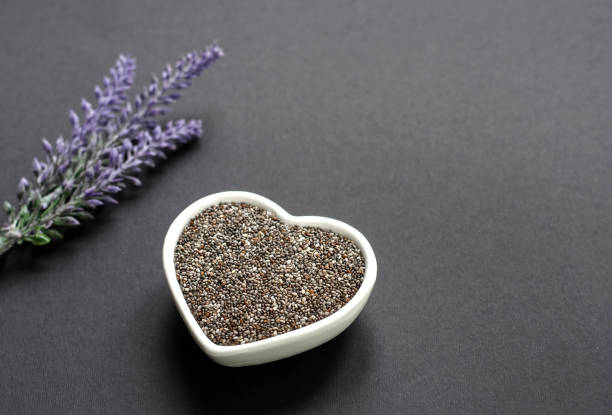 istock Organic chia seeds in a white heart bowl on black surface 1132108619
