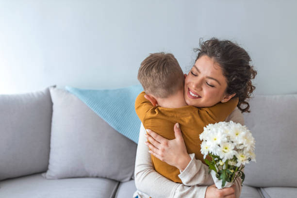 istock Son hugging happy mother with flowers. 1132115964