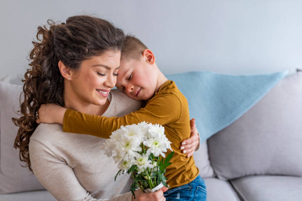 istock Son hugging happy mother with flowers. 1132116069