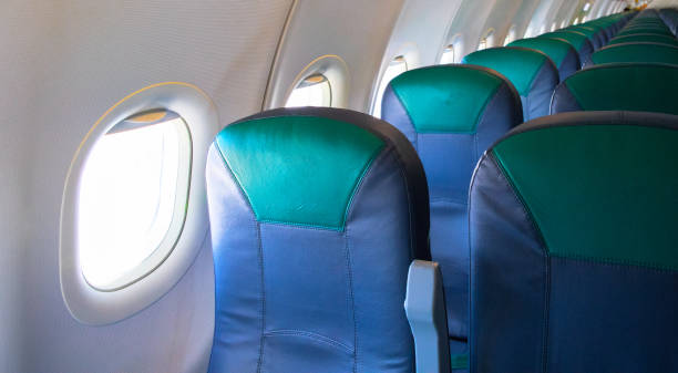 istock Empty airplane chairs and sunlight in illuminator. Aircraft interior photo. Empty plane waiting for passengers to load. 1132121788