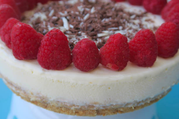 Close-up image of raspberries decorating homemade raspberry cheesecake cake dessert with grated milk and white chocolate