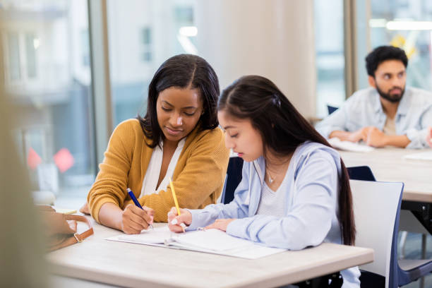 istock Female college friends study together in library 1132123705