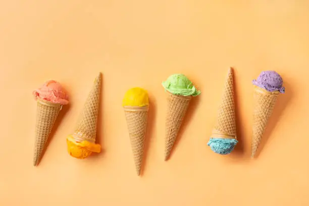 Top view of colorful ice cream cones on yellow backgound. Summer concept
