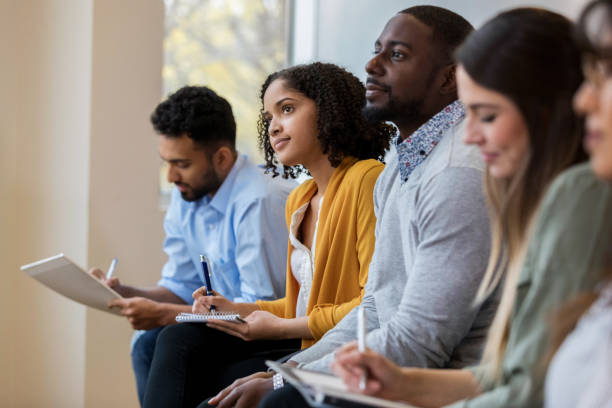 Group of business people concentrate during training class A group of business people sit in a row in a training class.  They look at an unseen speaker as they concentrate on his lecture. training course stock pictures, royalty-free photos & images