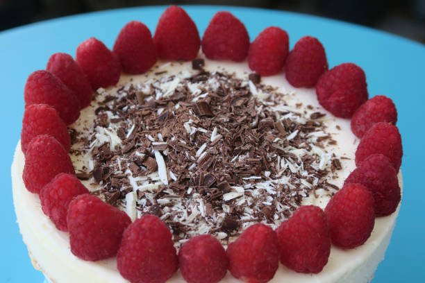 Image of whole gourmet homemade raspberry cheesecake cake dessert with grated chocolate and red berries in garden