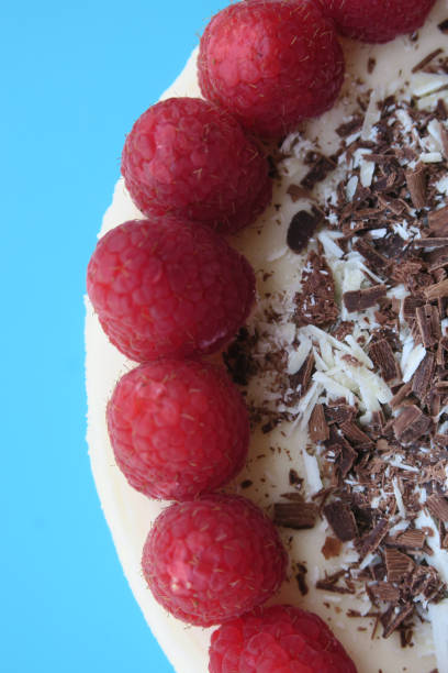 Image of uncut gourmet homemade raspberry cheesecake cake dessert with grated chocolate and red berries