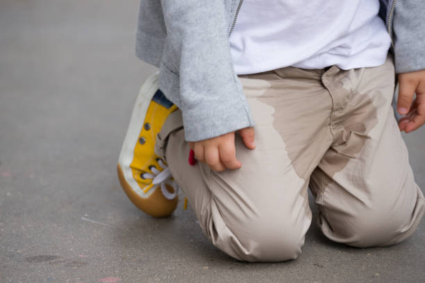 молодой парень мочиться на штаны на улице - кровать смачивания концепции. детская моча на одежду. - брюки стоковые фото и изображения