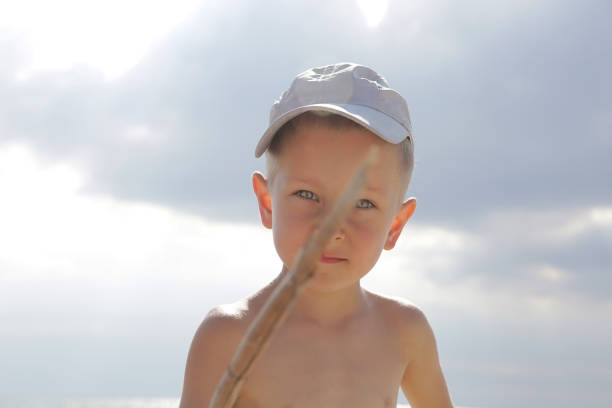 istock Bad little boy with a stick on the sea beach 1132128392
