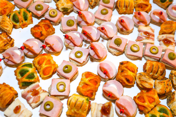 Festive table with people hands reaching for food, featuring a traditional Finnish sandwich cake voileipakakku in the center. Concept of celebration, togetherness, Nordic cuisine, and shared dining