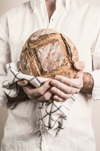 istock Rustic crusty loaf of bread in baker man's hands 1132128520