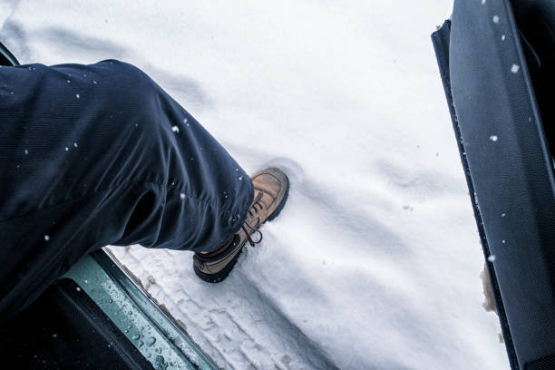 man es leg and shoe exiting car stepping into winter snow - snow track human foot steps stock-fotos und bilder