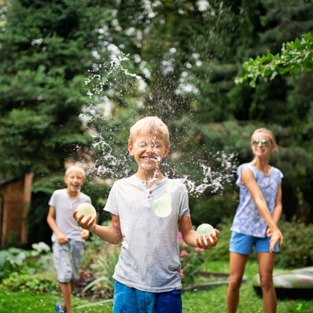 трое детей весело бросали бомбы с водой - balloon child elementary age people стоковые фото и изображения