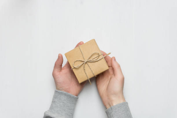 istock man's hands holds a gift in a box on a white wooden back 1132132003