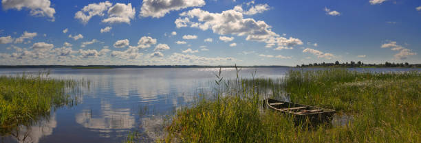 istock Summer panorama with a mirror lake and a boat at the shore 1132134030