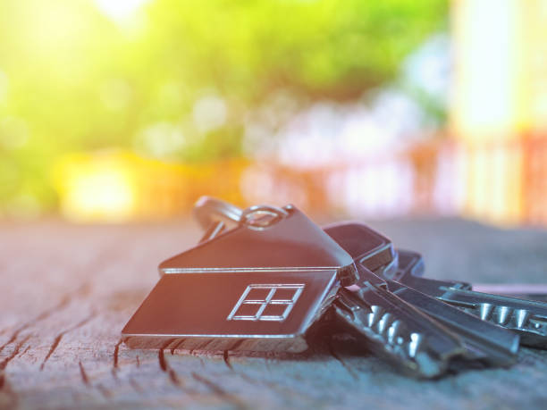 House keys with house figure on desk, out of focus background stock photo