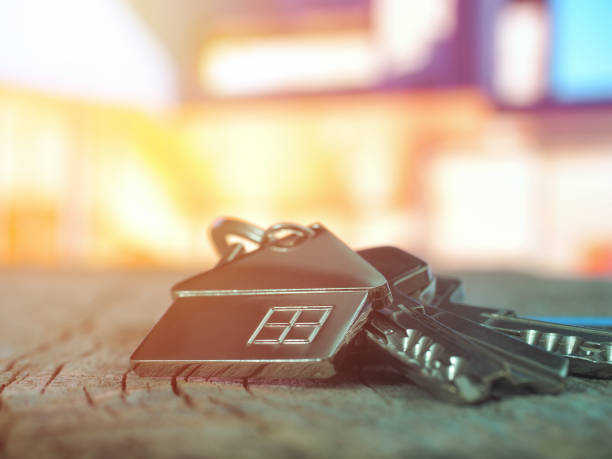 House keys with house figure on desk, out of focus background stock photo