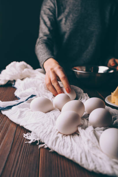 Female's hand takes egg to prepare dough for pie