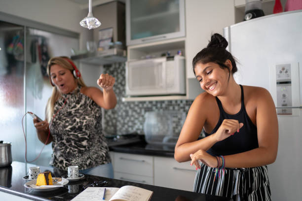 Mother and daughter having fun together while dancing in the kitchen