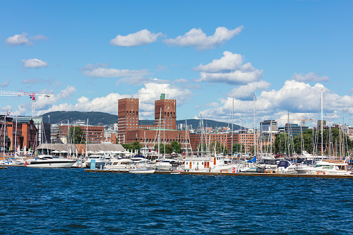 Oslo City Hall and yachts docked in the Oslofjord are captured on a summer day. Oslo City Hall is a municipal building in Oslo, Norway. It houses the city council, the city's administration and various other municipal organisations.