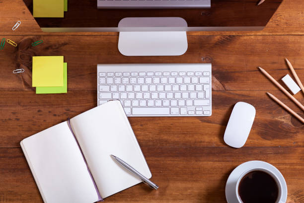 istock Work desk with computer monitor keyboard open notebook and coffee, modern desktop pc and supplies on workplace brown wooden business office table, device for education background, top view from above 1132152793