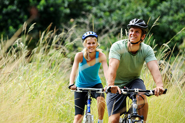 mountainbike couple outdoors Happy couple riding bicycles outside, healthy lifestyle fun concept cycling helmet photos stock pictures, royalty-free photos & images
