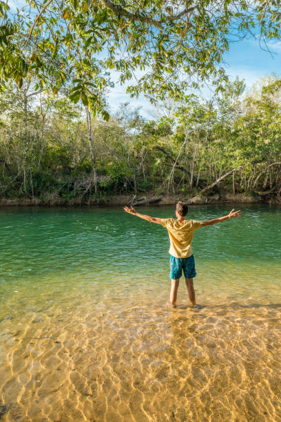 Man on shallow Formoso river in Bonito Man standing on shallow water with open arms, enjoying he weather and the river in Bonito, Mato Grosso do Sul, Brazil bonito brazil stock pictures, royalty-free photos & images