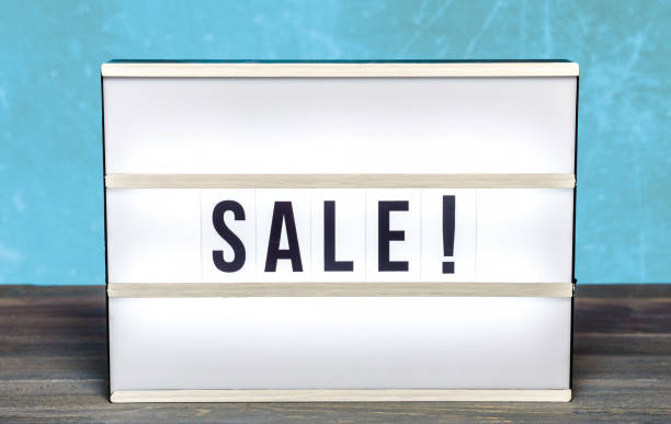 istock Light box with Sale letters against blue background on wooden table 1132162603