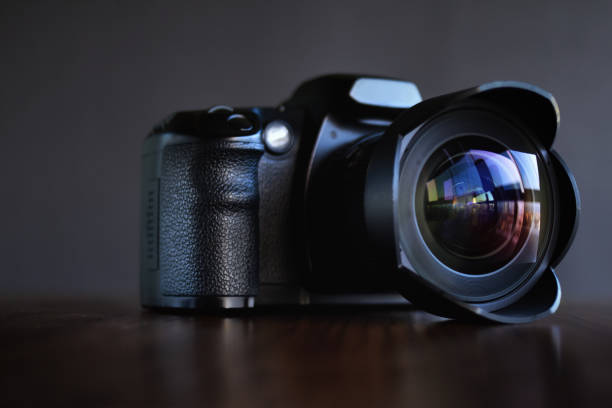 Digital single-lens reflex professional camera on wooden table and dark background
