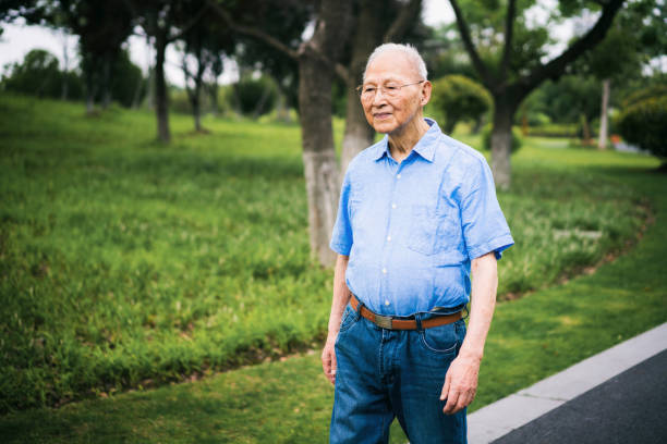 Senior Chinese man walking in a park.