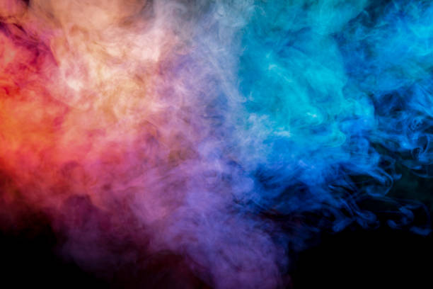 istock Translucent, thick smoke, illuminated by light against a dark background, divided into three colors: blue, green, pink and purple, burns out, evaporating from a steam of vape for print on t-shirt 1132176953
