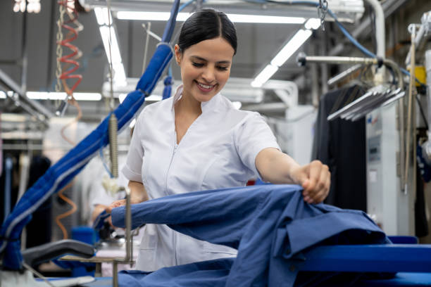 コインランドリーで働くラテンアメリカの若い女性は笑顔をアイロンで服 - press factory ストックフォトと画像