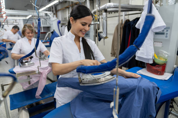 istock Cheerful young woman working at a laundromat ironing clothes smiling 1132178370