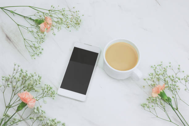 istock smartphone  and cup of drink with floral frame on a marble table 1132183862
