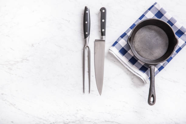 istock Empty pan on marble table with blue tablecloth knife and fork - top of view. 1132190491