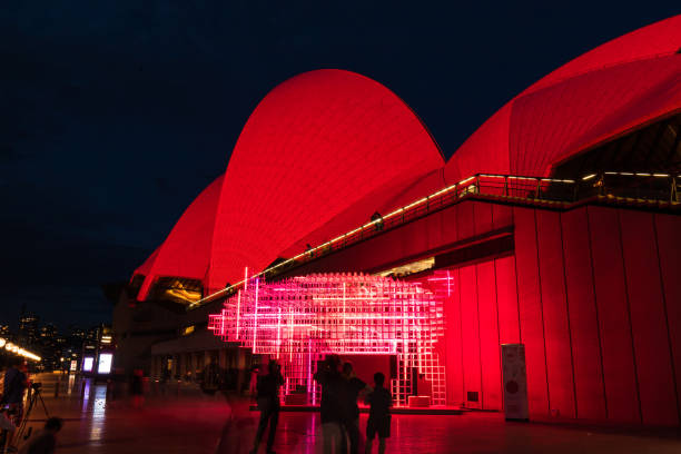 Sydney, Australia - February 4, 2019: Pig lunar lantern glowing pink in front of Sydney Opera House glowing red.