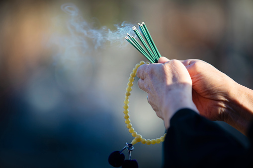 An item of the ceremony of the funeral of Japan, an incense stick.

The Japanese woman of the senior to hold an exiting incense stick of the smoke in a hand in a black mourning dress.