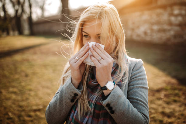 Sick blonde blowing her nose stock photo