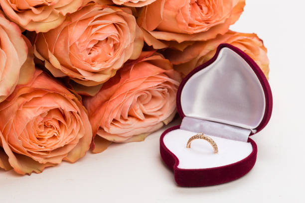 istock pink roses and box holding wedding ring on blue background - Image 1132202289