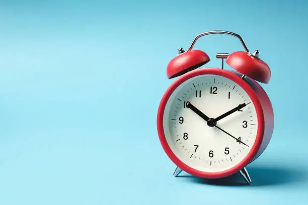 Photo of Red vintage alarm clock on light blue color background