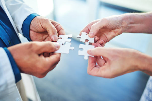 Where there's a question there must be an answer Cropped shot of two medical professionals connecting puzzle pieces together coordination stock pictures, royalty-free photos & images