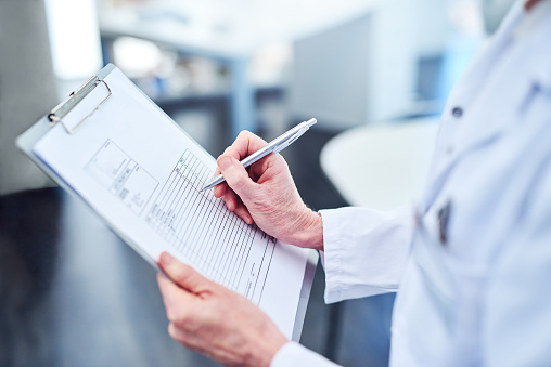 Cropped shot of a medical professional filling out paperwork