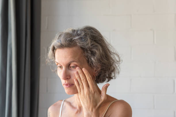 mujer de mediana edad frotando el ojo para limpiar el desgarro - frotarse los ojos fotografías e imágenes de stock