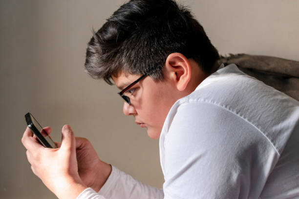 携帯電話の部屋のテキストメッセージングで10代の少年 - text messaging mobile phone teenagers only people ストックフォトと画像