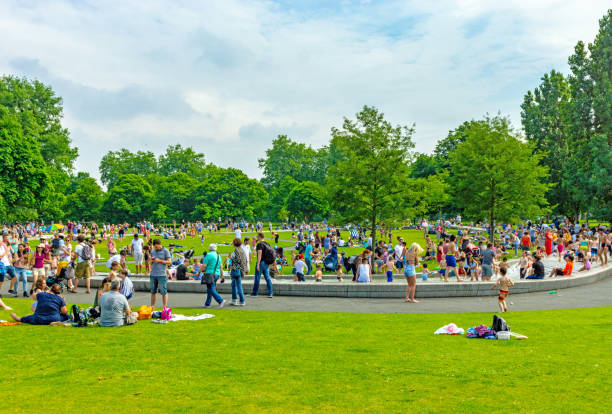 Princess Diana Spencer memorial in Hyde Park with large numbers of people in the water and sitting around the edge during the 2019 heat wave in London.
