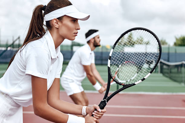 All or nothing. Beautiful woman and handsome man are competely focused on the game Young woman and man in white sportswear stand on the court with rackets in their hands fully concentrated on the game double be stock pictures, royalty-free photos & images