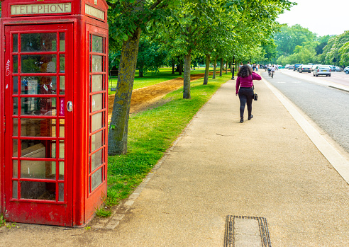 Iconic red BT telephone Booth on The Mall with an Afro Caribbean woman walking away from the camera.