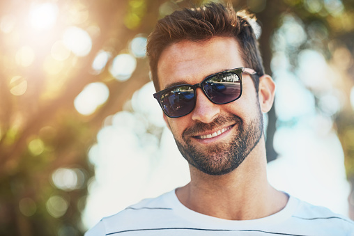 Cropped portrait of a handsome young man wearing sunglasses on a summer’s day outdoors