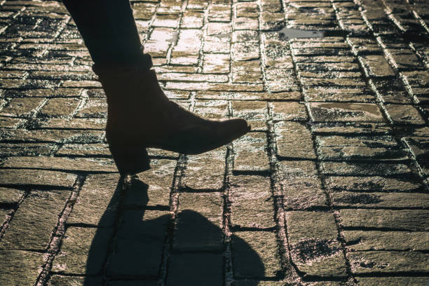 la donna cammina alla luce del sole sulla vecchia strada - at the bottom of boot sole of shoe shoe foto e immagini stock