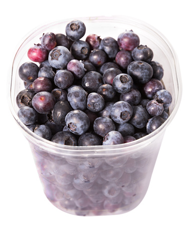 Fresh ripe blueberries in small plastic bucket. Isolated over white background